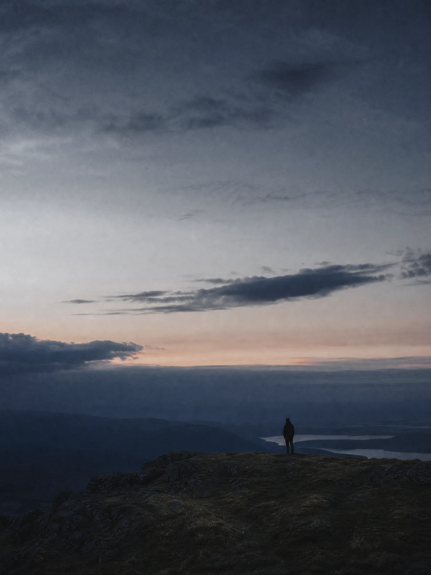 A solitary figure standing beneath an expansive evening sky